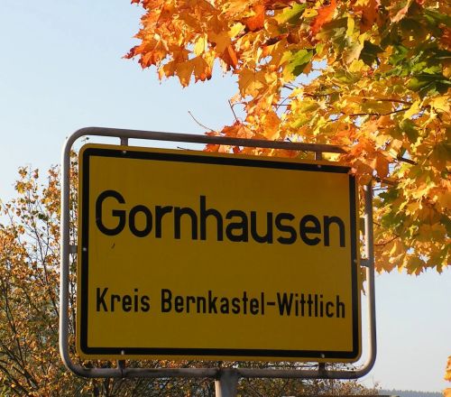 Ortsschild Gornhausen im Kreis Bernkastel Wittlich vor Herbstlaub und blauem Himmel